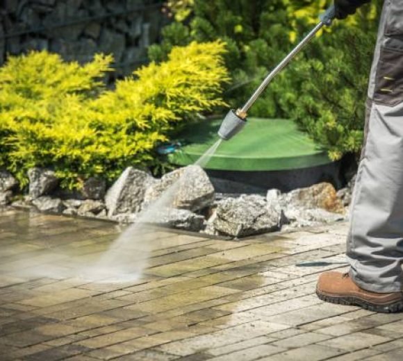 Cobble Brick Driveway Pressure Washing by Worker.